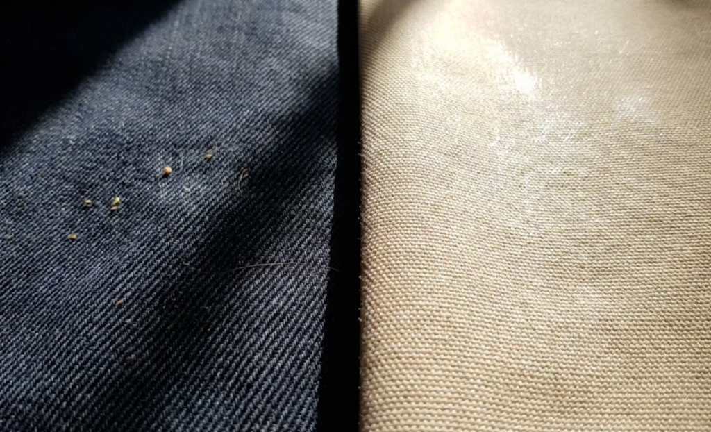 Close-up surface texture view showing the deep diagonal ridges of twill fabric that mask stains versus the smooth flat finish of duck canvas.