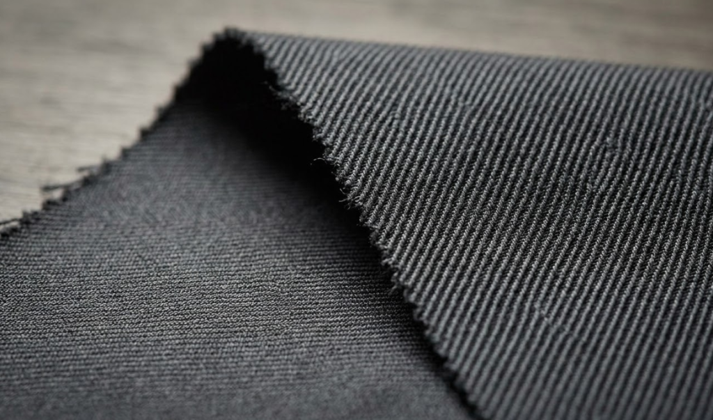 Macro close-up of gabardine fabric showing the steep diagonal wale angle on the face and the smooth reverse side.