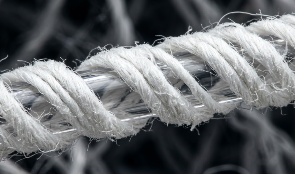 Microscopic view of a core-spun yarn construction demonstrating natural cotton fibers wrapped around a central polyurethane elastane filament.