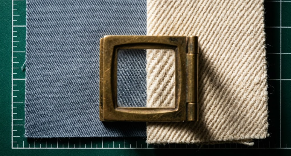 Macro photograph comparing the fine 2/1 diagonal weave of 5.5 oz lightweight cotton twill with the heavy 3/1 diagonal ridges of 14 oz bull denim under a brass linen tester loupe.